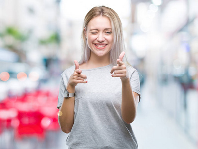 年轻的金发女人在孤立的背景下, 手指到相机与快乐和滑稽的脸。良好的能量和共鸣