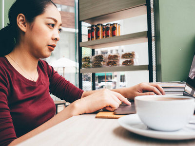 在咖啡馆里, 女人正在用笔记本电脑和一杯热咖啡