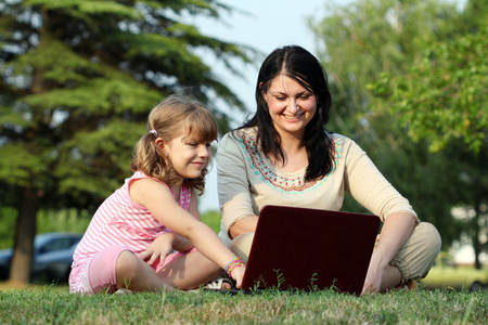 女孩和儿童配手提电脑在公园