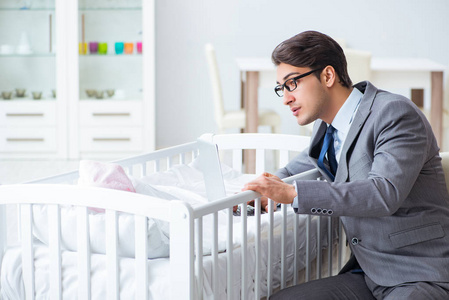 年轻的商人试图在家工作后照顾新生儿婴儿
