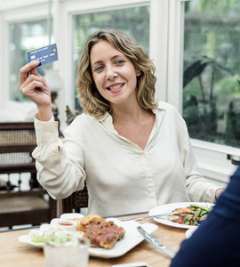 妇女支付午餐与信用卡在餐馆