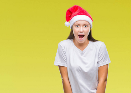年轻美丽的白人妇女戴着圣诞节帽子在孤立的背景害怕和震惊的惊讶的表情, 恐惧和兴奋的脸