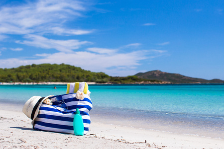 条纹袋 草帽 防晒霜和白色的热带海滩上的毛巾