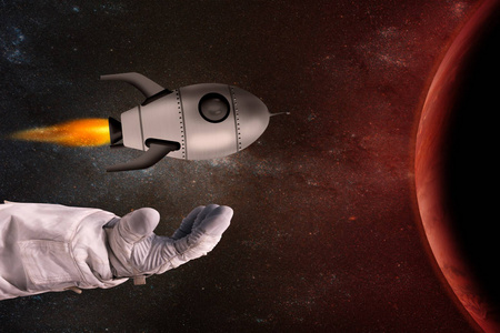 玩具火箭在宇航员的手在红色行星对面