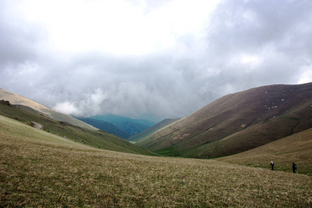 美丽的山景山灰色多云的天空吉尔吉斯斯坦。风景秀丽的高山景观与山脉和游客的背景