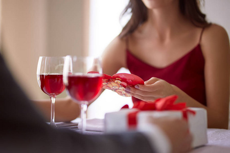 美丽的情侣在餐厅庆祝情人节, 喝葡萄酒, 分享礼物, 享受彼此