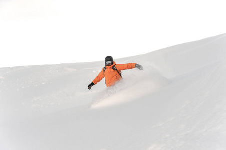 橙色运动服滑雪运动员骑在粉山斜坡对明亮的白色天空