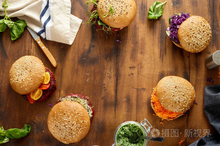 素食汉堡与甜菜肉片和李子, 芝麻菜和苜蓿在木桌上, 顶部视图