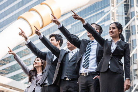 成功的亚洲商业团队用手指来庆祝他们的胜利。团队合作和成功理念
