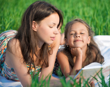 在绿色草地上读书的女孩
