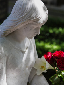 美丽的雕塑一个悲伤的女孩在阳光明媚的花园