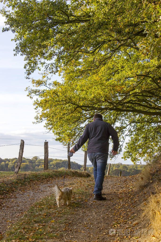 在森林里遛狗的男人照片-正版商用图片07iq8r-摄图新视界