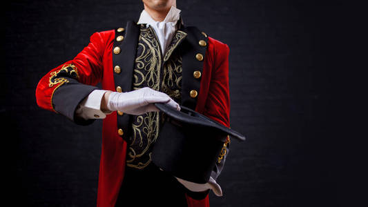 魔术家魔术师.手在手套的特写在红色背心和圆筒的家伙照片