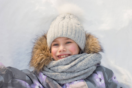 年轻的微笑的女孩正在雪地里玩耍和躺着。