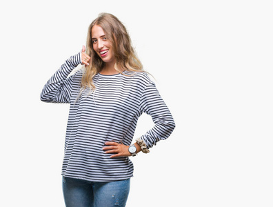 美丽的年轻金发女子穿条纹毛衣在孤立的背景微笑做电话手势用手和手指喜欢说话的电话。沟通概念