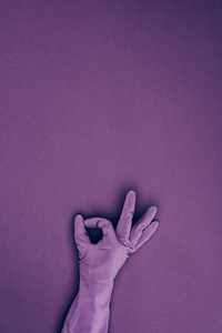 裁剪图像的妇女显示 ok 标志橡胶防护手套在紫色隔离