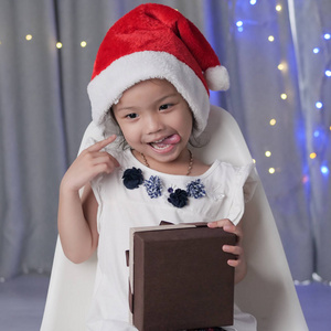 愉快的亚洲女孩佩带圣诞老人帽子和打开礼物盒, 圣诞节概念