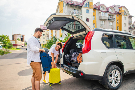 汽车旅行概念。打开行李箱内的妇女与男子附近。道路旅行