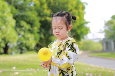 可爱的小女孩使用塑料空气泵气球在公园的一个晴朗的日子