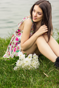美丽年轻的黑发女人坐在草丛中的一束鲜花