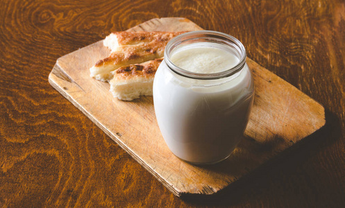 在玻璃罐子里的酸牛奶, 一块亚洲的木制面包板