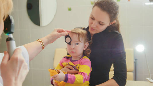 诊所的女人视光师检查在小女孩childs 眼科视力