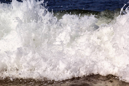 在海浪中, 泡沫的海浪在沙滩上爆发。背景图像