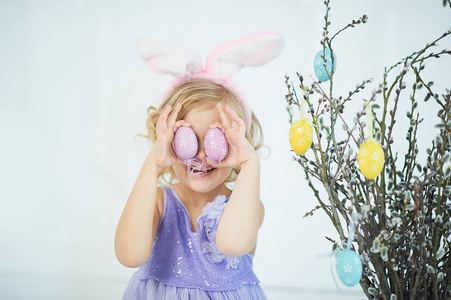 可爱的滑稽的女孩在家里玩彩色复活节彩蛋