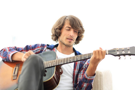 英俊的男人，在家里的沙发上吉他演奏