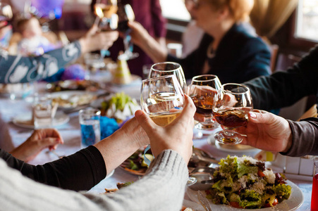 人们手捧着白红葡萄酒和美味的菜肴在 tableasses 和烘烤, 快乐的节日时刻, 奢华的庆祝理念的杯子