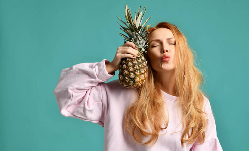 年轻快乐美丽的女人亲吻和举行菠萝水果