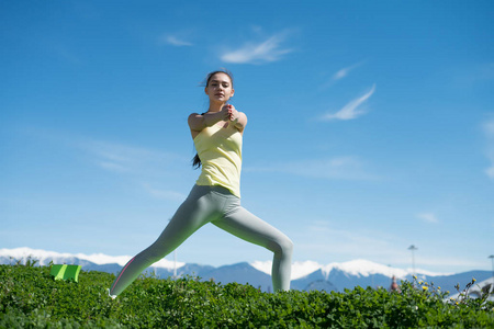 自信的年轻女孩做瑜伽在绿色的草地上, 在一个温暖的春天的一天, 伸展