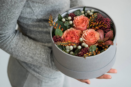 灰色盒子中女性手持美丽玫瑰花装饰特写