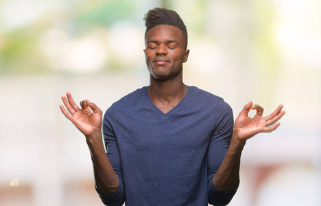 在孤立的背景下, 年轻的非洲裔美国人放松和微笑闭上眼睛做冥想手势用手指。瑜伽理念