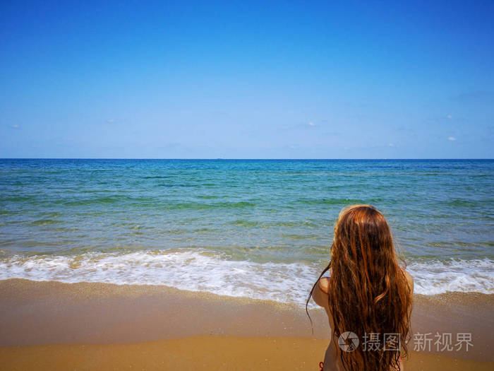 美丽的女孩转身在海边他的背部