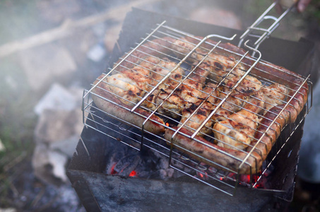 在字段中炸羊肉串从鸡翅膀。在露天的经典烧烤。煎肉的木炭的过程