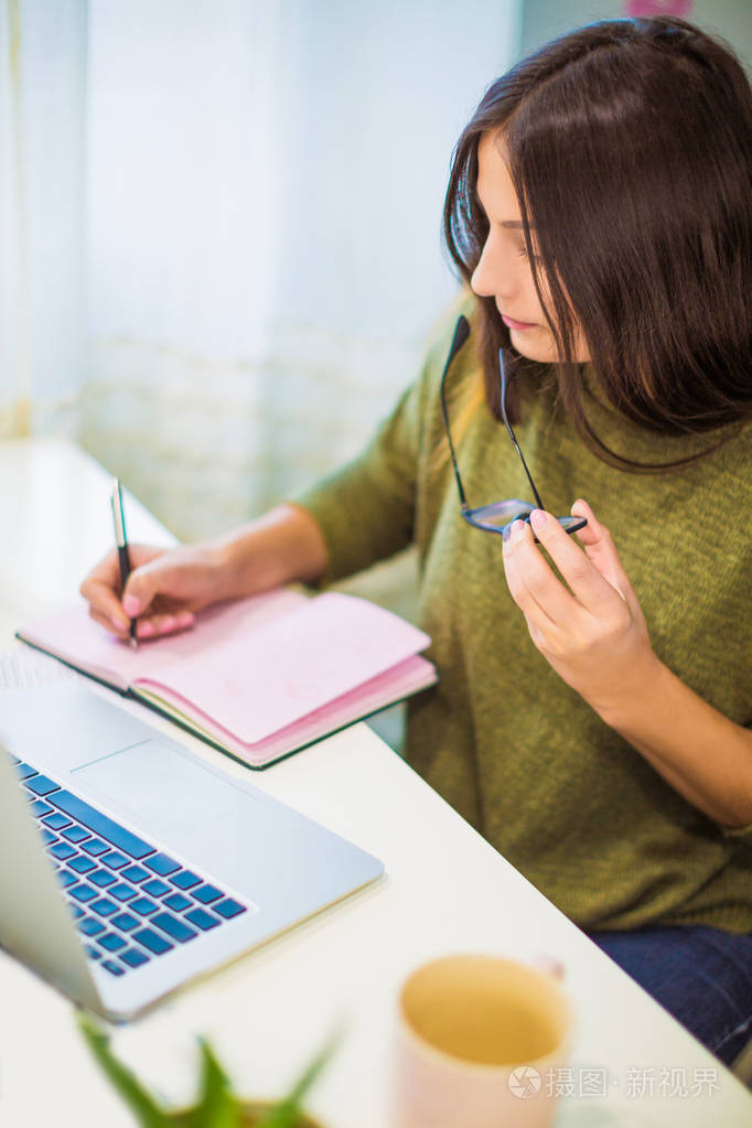 在家里坐在桌子上写字的年轻女人的肖像