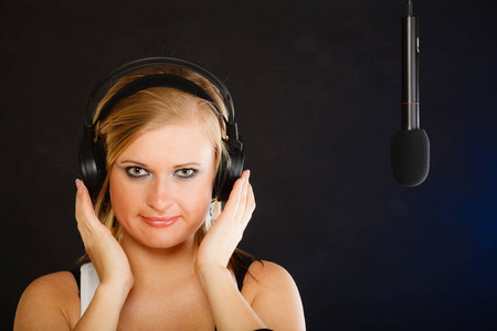 对在播音室里戴着耳机的麦克风唱歌的女人
