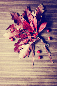 秋天背景用叶子和莓果在木表面制成的花束