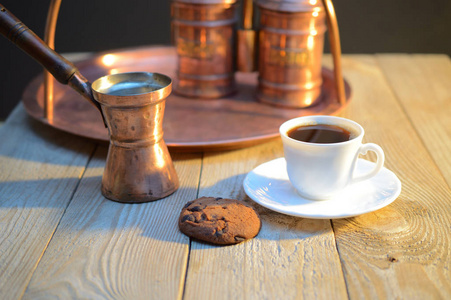 一个饼干和一杯咖啡在糖碗附近和一个容器与咖啡在质朴的木桌