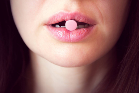 粉红色片剂在妇女的嘴里