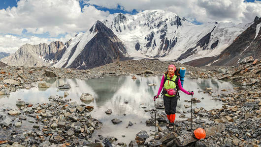 一个妇女冒险家和登山者在一个山通行证附近在冰川在盔甲和与背包