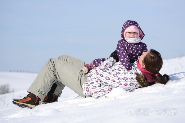 母亲坐在雪橇在公园中与儿童在冬季