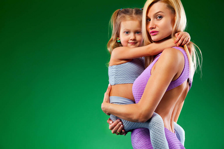 哈他瑜伽健身。年轻的母亲和女儿一起在室内锻炼。家庭外观