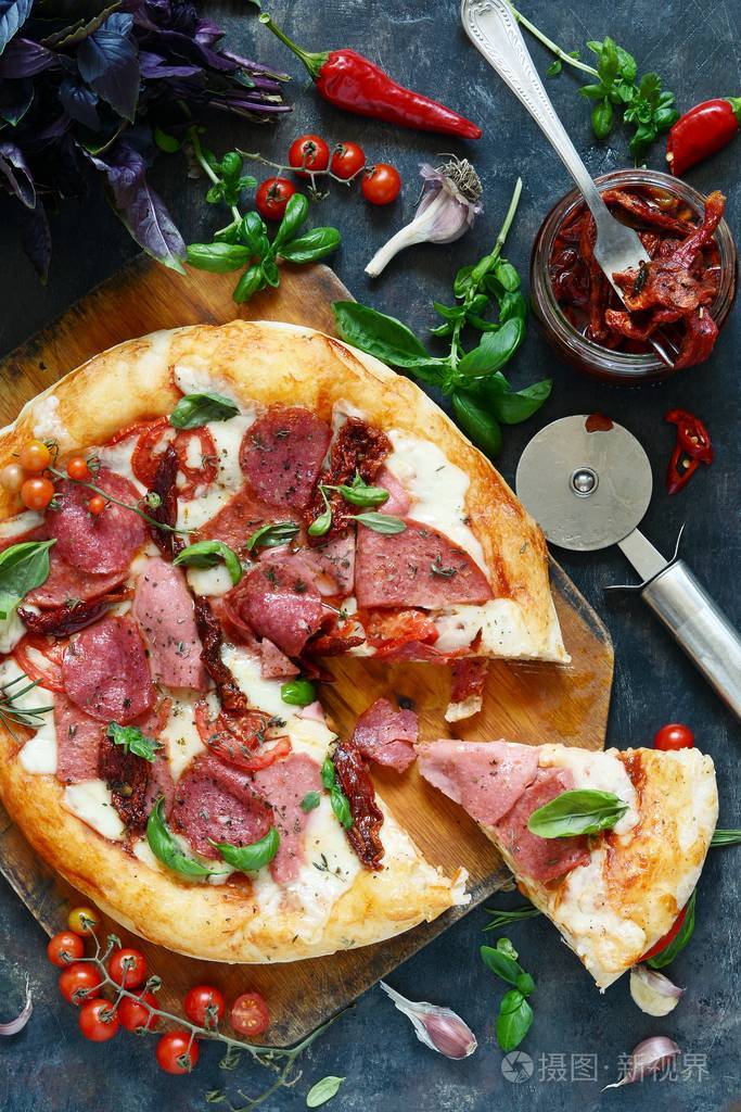 传统的意大利比萨与干香肠西红柿干酪樱桃西红柿和新鲜的绿色罗勒叶