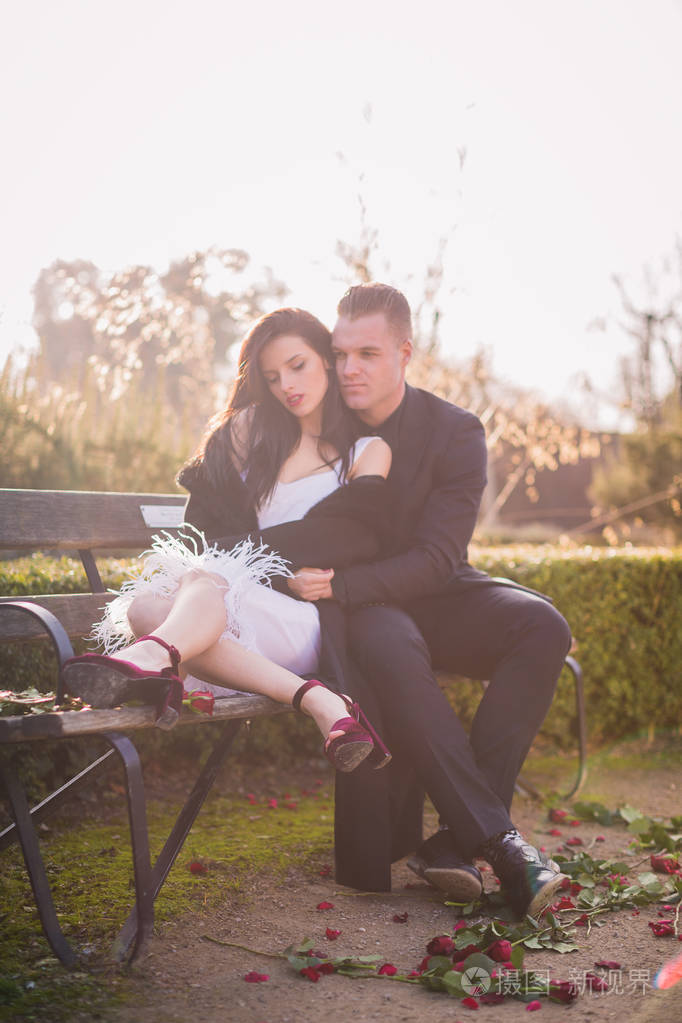 两个美丽的人相爱, 坐在长椅上的怀抱, 户外