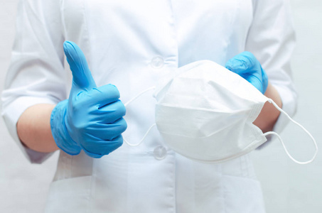 医用口罩在医生手里穿着蓝色的医用手套。使用医用口罩预防疾病