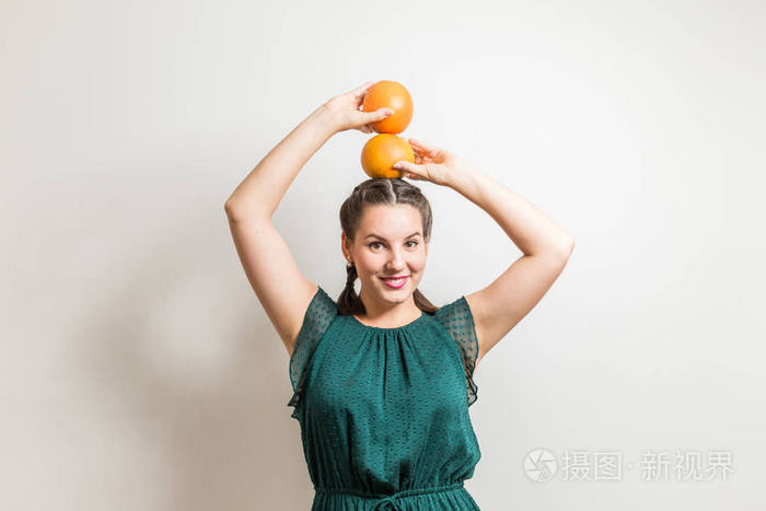 快乐的笑的女孩摆在她的头上葡萄柚