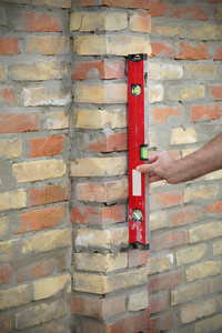工人建筑与控制砖墙使用水平工具