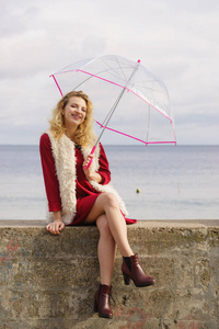 快乐优雅的成年女子手持透明伞对抗天空。天气预报概念